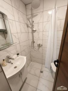 a white bathroom with a shower and a sink at Emara Lodge Bansko in Bansko