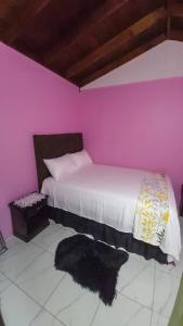 a bedroom with a bed with a pink wall at Cozy Get Away in Portmore