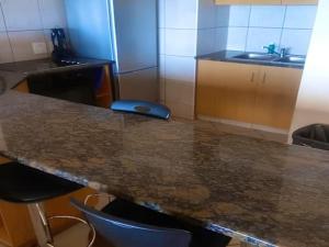 a kitchen with a granite counter top and chairs at Lescalier 513 Luxury sea facing unit in Amanzimtoti +9 photos