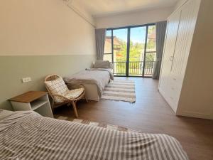 a bedroom with two beds and a window with a balcony at Sharing Pool Villa Sritanu in Ko Phangan