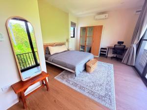 a bedroom with a bed and a mirror and a chair at Sharing Pool Villa Sritanu in Ko Phangan +3 photos