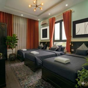 a bedroom with two beds with red curtains at Muse Riverside in Ninh Binh