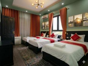 a hotel room with two beds with red curtains at Muse Riverside in Ninh Binh