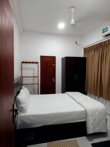 a bedroom with a white bed and a brown door at Skyline Residence in Wadduwa