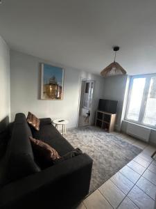 a living room with a black couch and a table at Centre ville - Berthelot in Chamalières