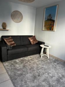 a living room with a black couch and a table at Centre ville - Berthelot in Chamalières +1 photo