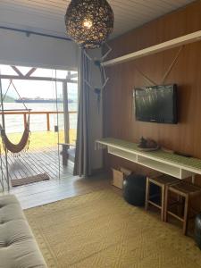 a living room with a tv on a wall and a couch at Piaça House - Piaçaguera -Pr in Paranaguá