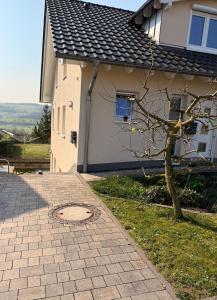 a house with a tree next to a sidewalk at Auszeit in Bad Sobernheim