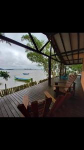 a deck with chairs and a table and a view of the water at Piaça House - Piaçaguera -Pr in Paranaguá