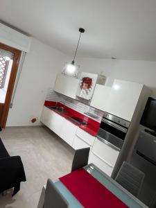 a kitchen with white cabinets and a red counter top at Bilocale Le Rose in Vada