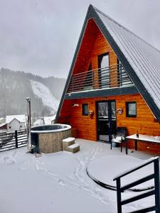 a log cabin with a hot tub in the snow at Twin Cabins Azuga in Azuga