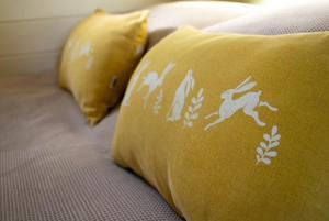 a yellow pillow with a horse on it on a bed at Halcyon - Shepherd's Hut in Northrepps