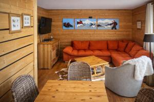 a living room with an orange couch and a table at Hôtel Chalet Alpage in La Clusaz