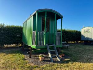 a green train car parked in a yard at Halcyon - Shepherd's Hut in Northrepps
