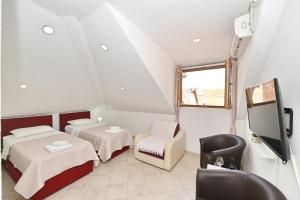 a room with two beds and a tv and a chair at Old town central in Kotor