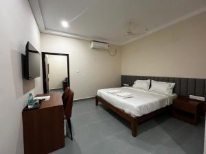 a bedroom with a bed and a desk and a mirror at Rangoli Suites & Restrobar in Bantvāl