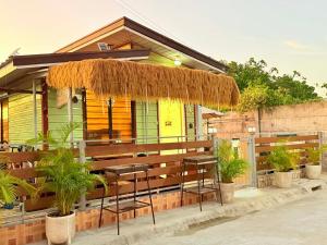 a bar with a straw umbrella and stools in front of a house at Olango Island-Tiny Guest House Fully Furnished with Hot Shower, Washer, Wi-Fi, Netflix & King Bed S&E-3 in Lapu Lapu City
