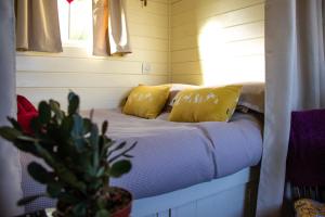 a couch in a room with yellow pillows and a plant at Halcyon - Shepherd's Hut in Northrepps