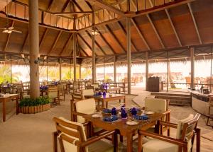 a restaurant with wooden tables and chairs and a large tent at Filitheyo Island Resort in Filitheyo +39 photos
