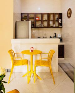 a kitchen with a yellow table and two chairs at Sakina Nook in Arusha