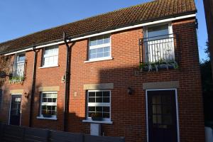 a red brick house with windows and a door at Frinton Escapes - The Cottage in Frinton-on-Sea