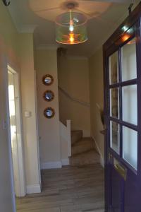 a hallway with a staircase and a ceiling with a light at Frinton Escapes - The Cottage in Frinton-on-Sea