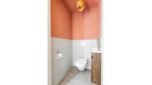 a bathroom with a toilet and orange walls at Forest Villa De Bosburcht with Sauna | 6 persons in Gasselte +47 photos