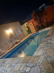 a swimming pool at night with chairs and a house at Pousada Allmar in Bertioga