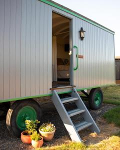 a trailer with a door open and some potted plants at Galahad - Shepherd's Hut in Northrepps