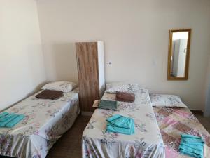 two twin beds in a room with a mirror at Pousada Paraíso in Telêmaco Borba