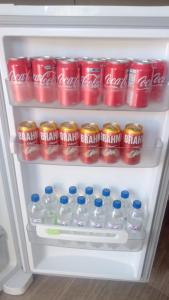 an open refrigerator filled with cans and bottles of soda at Pousada Paraíso in Telêmaco Borba