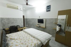 a bedroom with a bed and a tv on a wall at Sri Kalki Jamjam Resort in Erode +2 photos