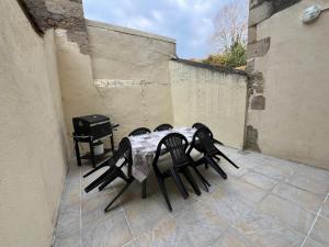 a table and chairs on a patio with a grill at Le gîte nivernais in Varzy