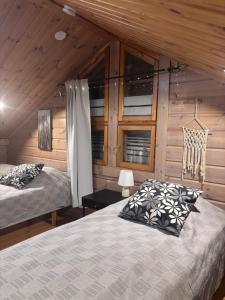 a bedroom with two beds and wooden walls at Latvahonka Cottage in Jämsä