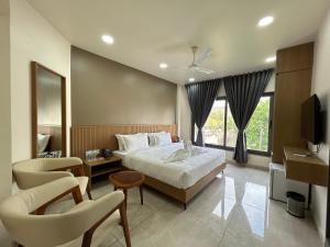 a hotel room with a bed and a tv and chairs at V Club in Bhuj