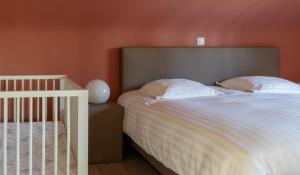 a bedroom with a white bed and a crib at Vakantiewoning Kastijd Kortessem - Haspengouw in Kortessem