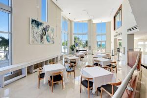 a dining room with tables and chairs and windows at Marenas Resort Beachfront Condo with Direct Access in Sunny Isles Beach