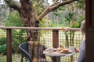 a woman sitting on a porch with a table with a vase of flowers at Mertrick in Forest Mill