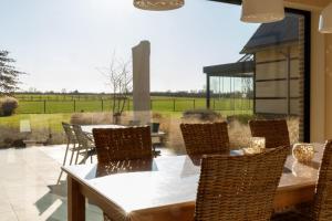 a patio with a table and chairs and a view of a field at Vakantiewoning Kastijd Kortessem - Haspengouw in Kortessem