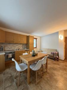 a kitchen with a wooden table and white chairs at Ca' de Mario in Sondalo