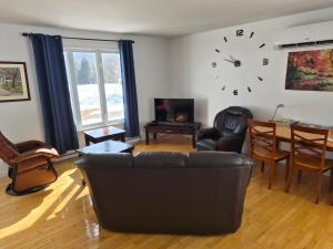 a living room with a couch and a clock on the wall at Maison Albert in Petite-Vallée
