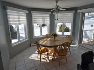 a dining room with a table and chairs and windows at Maison Albert in Petite-Vallée