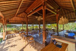 an outdoor restaurant with wooden tables and chairs at Cahya Restu Ubud Villa in Ubud