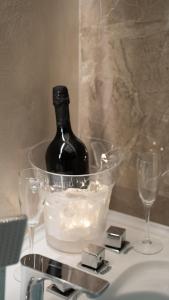 a bottle of wine in a bucket on a sink with two glasses at Elysium suites & Spa in Barletta +21 photos