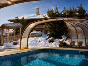 a swimming pool with a gazebo next to a house at Hôtel Chalet Alpage in La Clusaz