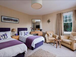 ein Hotelzimmer mit zwei Betten und einem Stuhl in der Unterkunft Ards House in Oban