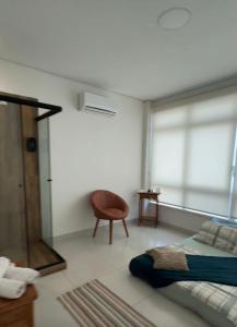 a bedroom with a bed and a chair and a window at Solua Hostel in Santos