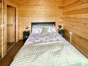 a bed in a wooden cabin with two night stands at Wind Hall Log Cabin in Gosforth