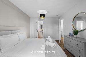 a white bedroom with a large bed and a mirror at Spacious 5 Bed House in Reading by Amber Stays, Perfect for Business & Contractors, Sleeps 12 in Reading