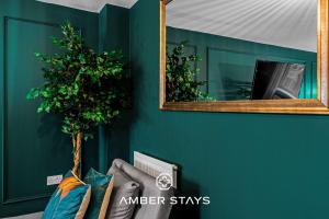 a mirror on a wall with a couch and a plant at Spacious 5 Bed House in Reading by Amber Stays, Perfect for Business & Contractors, Sleeps 12 in Reading